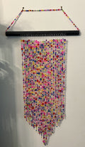 Multicolored beaded wall hanging on a plain background